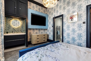 A bedroom with a bed, a TV mounted on the wall, a mirror, and a dresser. - 2 Bedford House - Close to Town and Seafront (Tenby)