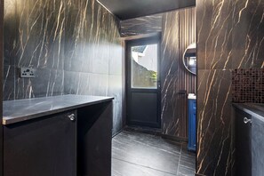A modern bathroom with dark marble walls, a sink, and a door leading outside. - 2 Bedford House - Close to Town and Seafront (Tenby)