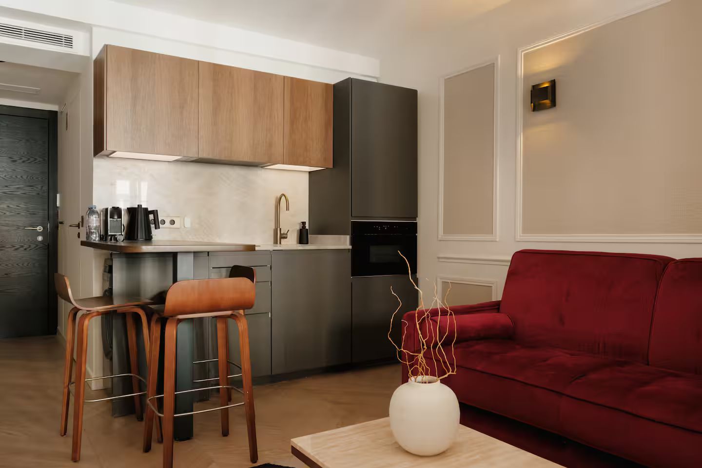 A modern kitchen with a built-in island, a red sofa, and a coffee table with a vase.