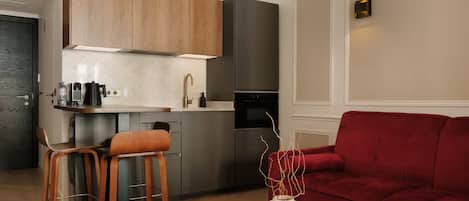 A modern kitchen with a built-in island, a red sofa, and a coffee table with a vase.