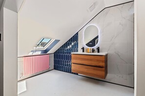 Ein modernes Badezimmer mit Dachfenster, einem Waschtisch mit Spiegel und einer Wand mit Muster.