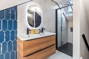 Ein modernes Badezimmer mit einem Holzlager, einem runden Spiegel und einer Duschkabine aus Glas.