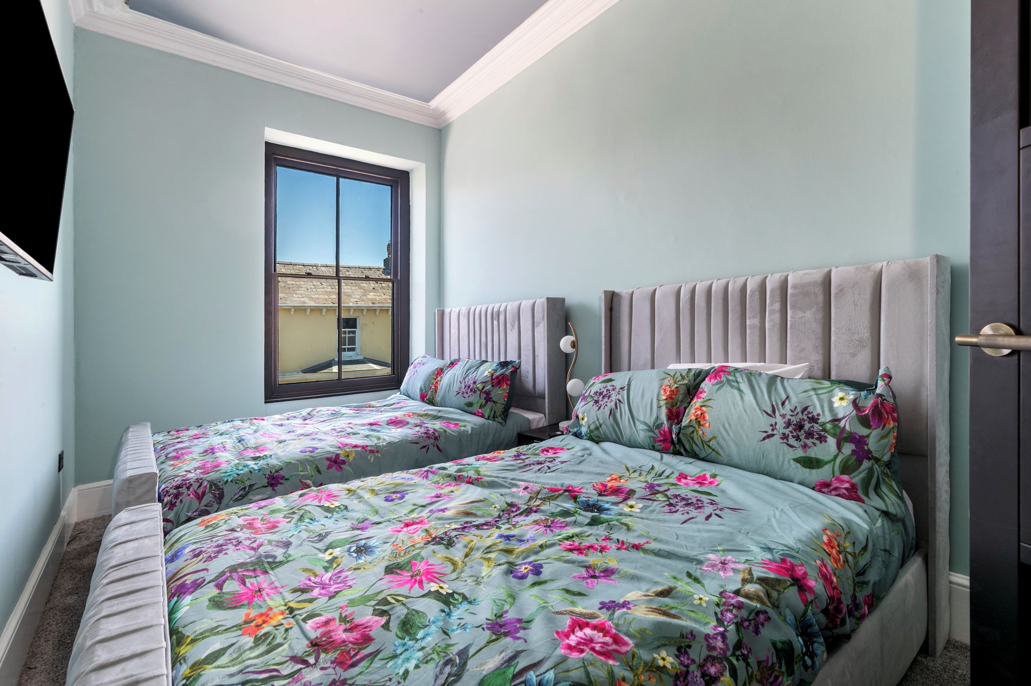 Ein Schlafzimmer mit zwei Betten, einem Fenster und einer Tür.