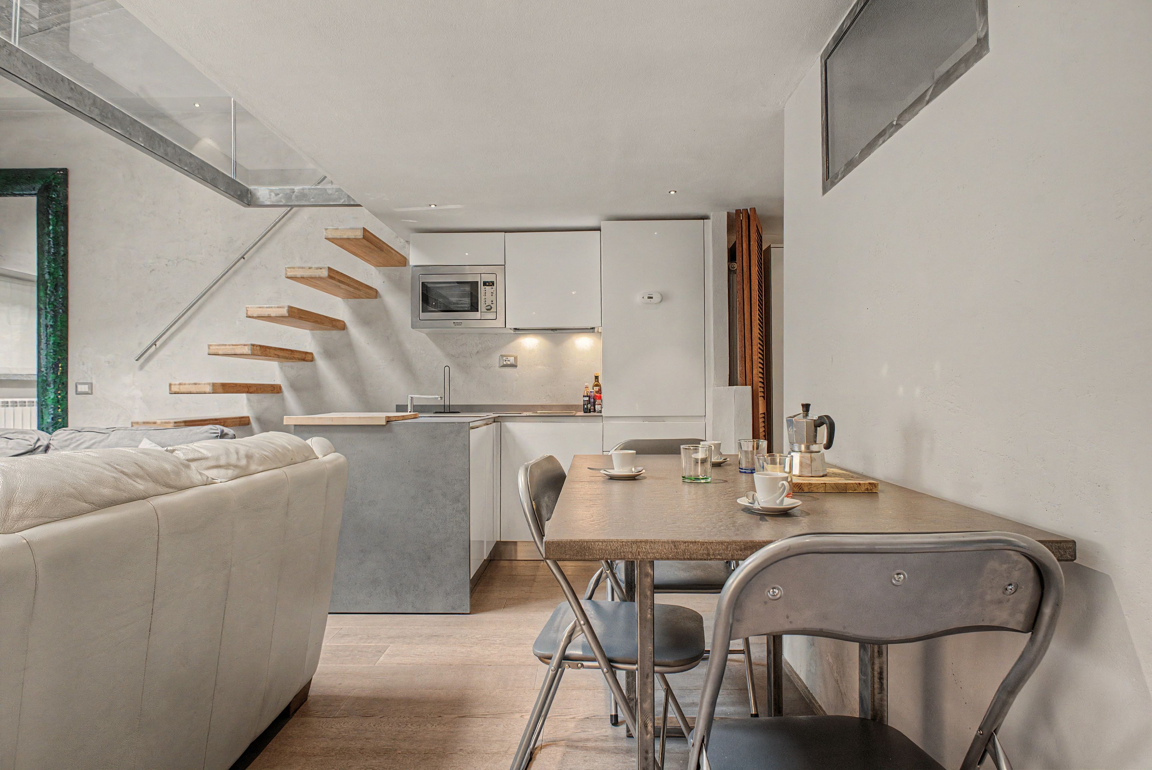 Une cuisine moderne dotée d’un îlot central, d’une table à manger avec des chaises et d’un escalier menant à un niveau supérieur.
