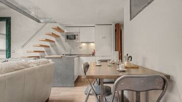Une cuisine moderne dotée d’un îlot central, d’une table à manger avec des chaises et d’un escalier menant à un niveau supérieur.