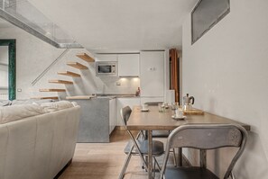 Une cuisine moderne dotée d’un îlot central, d’une table à manger avec des chaises et d’un escalier menant à un niveau supérieur.