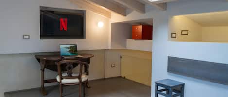 Una habitación con escritorio, silla, cama y televisor montado en la pared.