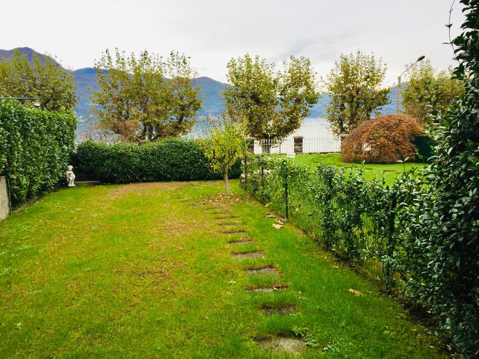 Un jardin bien entretenu, avec un chemin bien défini, une végétation luxuriante et une vue sur les montagnes en arrière-plan.