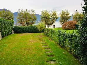 Un jardin bien entretenu, avec un chemin bien défini, une végétation luxuriante et une vue sur les montagnes en arrière-plan.