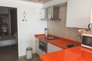 Eine kleine Küche mit roter Arbeitsplatte, einer Mikrowelle und einem Spülbecken.