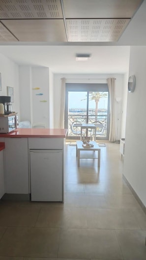 A modern kitchen with a built-in dishwasher, a dining area with a table and chairs, and a view of the sea through a large window. - Mar Y Sol Caleta Marina 2A (Algarrobo-Costa)