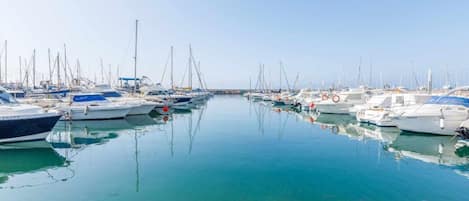 A marina with multiple boats docked in calm waters, surrounded by rocky terrain.