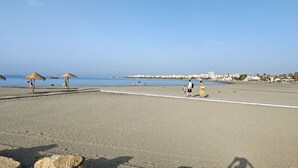 Ein Strand mit Sonnenschirmen, blauem Himmel und ruhiger See.