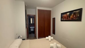 Ein Hotelzimmer mit Bett, einem Gemälde an der Wand und einem durchgegangenen Tür erkennbaren Badezimmer.