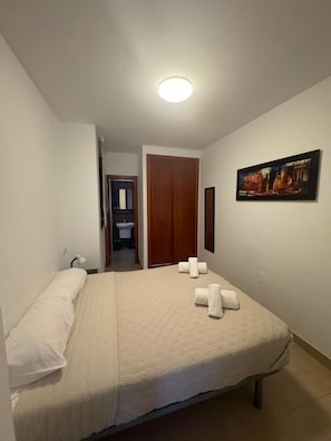 A hotel room with a bed, a painting on the wall, and a bathroom visible through an open door. - Mar Y Sol Caleta, Mar Y Sol Puerto -1A (Algarrobo-Costa)