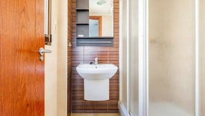 Ein Badezimmer mit Holztür, Waschbecken und einem Spiegel darüber.