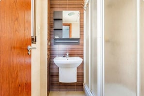 A bathroom with a wooden door, a white sink, and a mirror above it. - Mar Y Sol Caleta, Mar Y Sol Puerto -1A (Algarrobo-Costa)