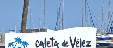 A sign with 'Caleta de Vélez' and 'Costa del Sol' indicating a coastal location.