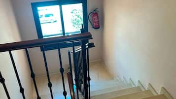 Una escalera con barandilla y un ventanal que ofrece vista a un vehículo afuera.