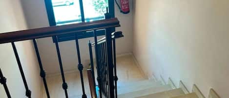 A staircase with a handrail and a window with a view of a vehicle outside.