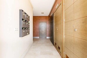 Un couloir avec une rangée de casiers sur le côté gauche et une porte en bois sur le côté droit.