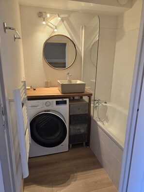 A compact bathroom with a washing machine, a sink, and a bathtub. - Flat with sleeping area, balcony & indoor swimming pool (Saint-Sorlin-d´Arves)