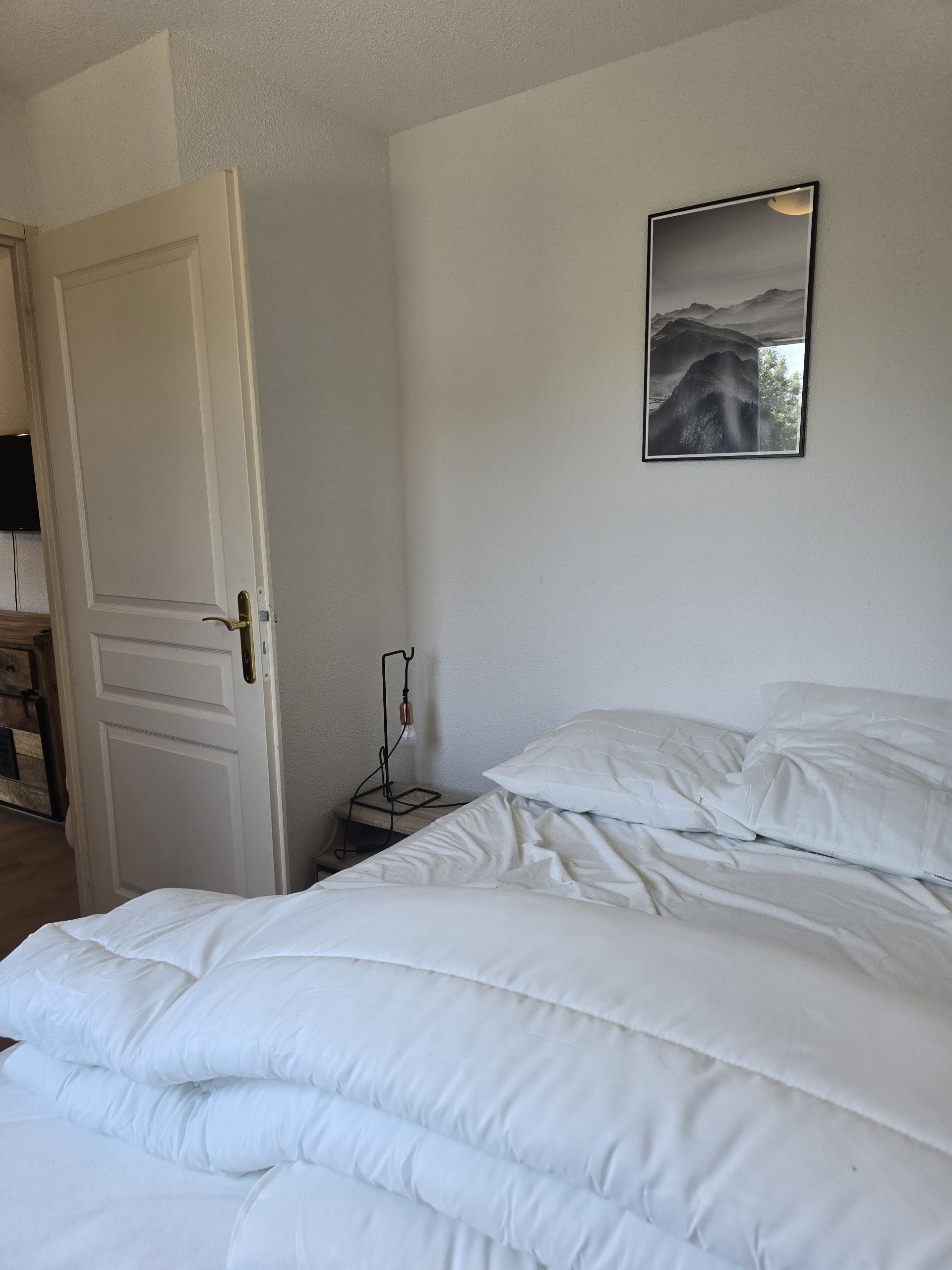 Une chambre à coucher avec un lit, une table de chevet, une lampe et un tableau encadré au mur.