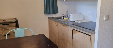 Una cocina compacta con armarios de madera, un microondas y un comedor con una mesa y sillas.