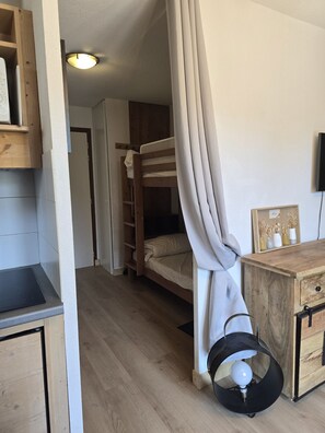 A room with a bunk bed, a wooden cabinet, a small table, and a wall-mounted TV. - Flat with sleeping area, balcony & indoor swimming pool (Saint-Sorlin-d´Arves)