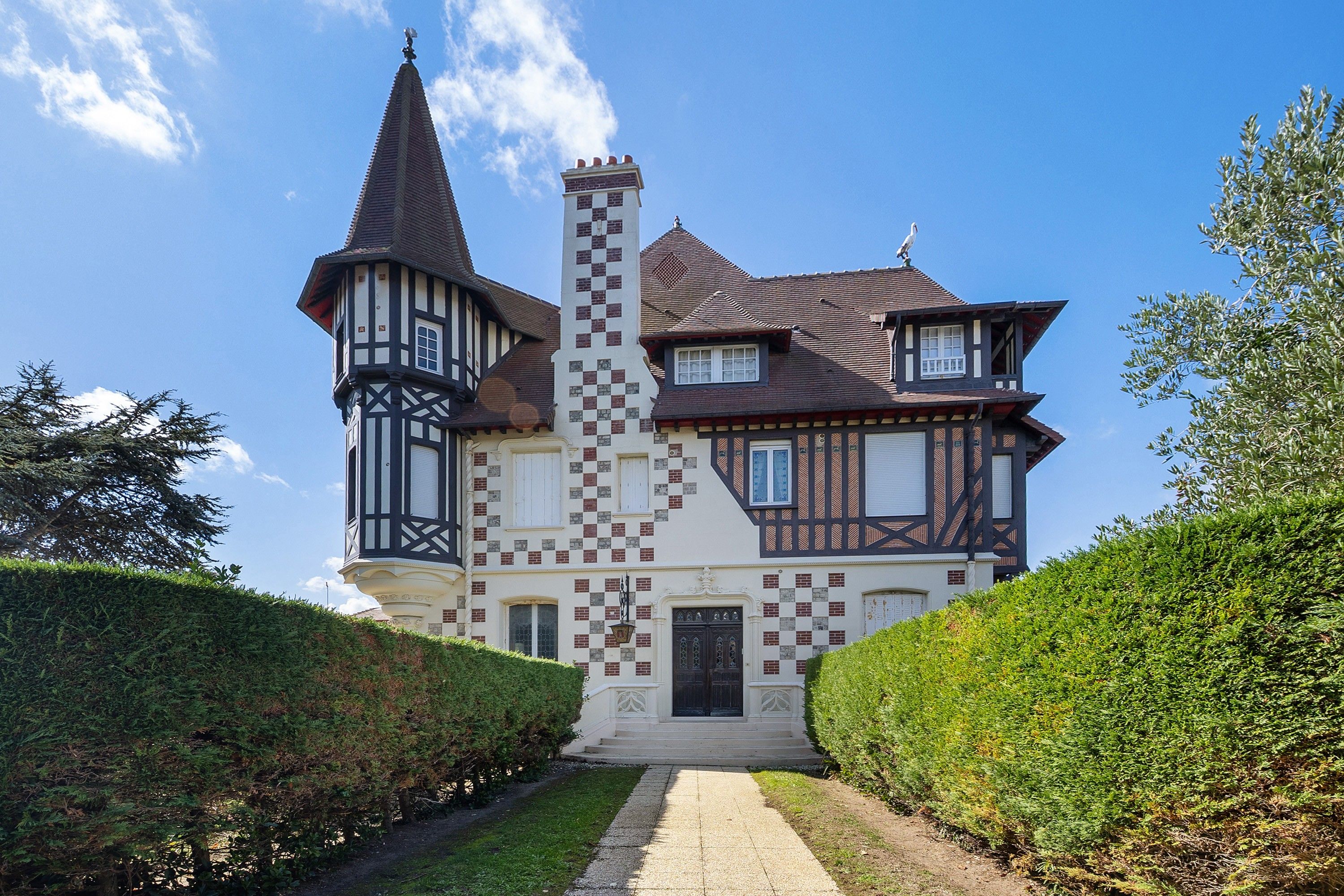 Un grand bâtiment historique, doté d’une tour imposante, d’une cheminée centrale et d’une façade symétrique.