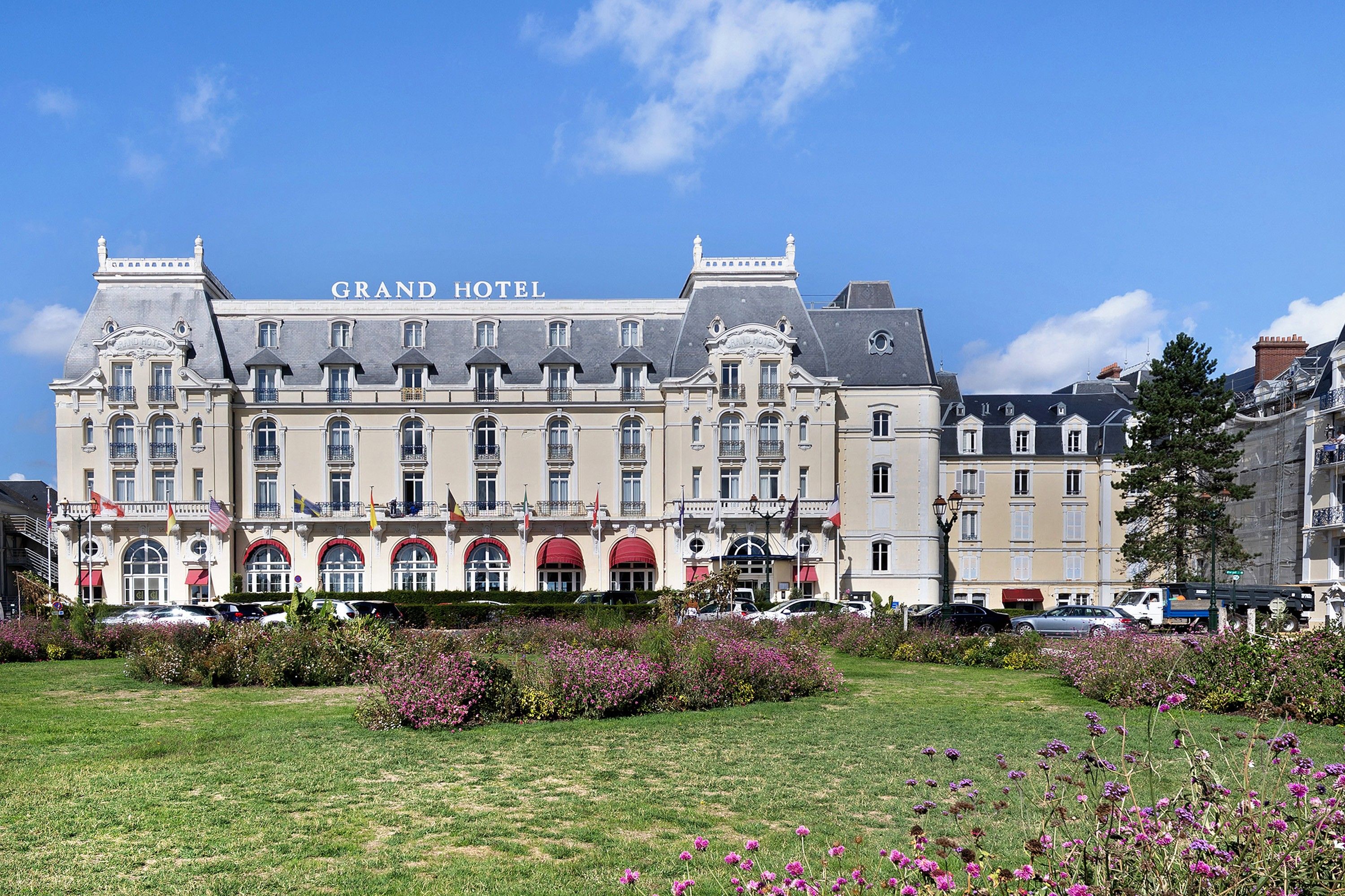 Un grand bâtiment historique, surmonté d’une enseigne indiquant « GRAND HÔTEL », qui présente une architecture classique avec de nombreuses fenêtres et des balcons.