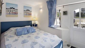 Ein Schlafzimmer mit Bett, Nachttisch, einem Fenster mit Vorhängen und Wandbildern.