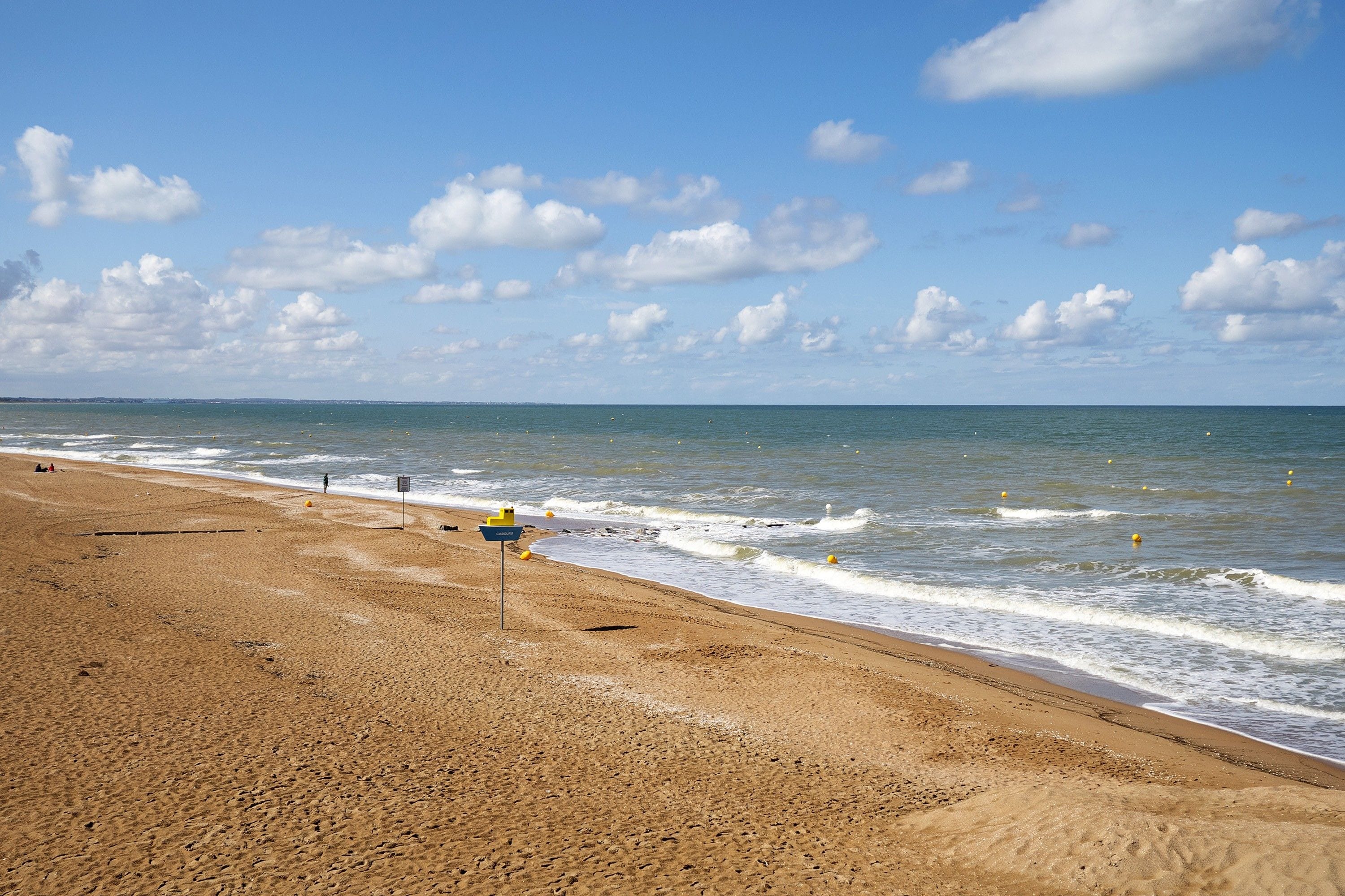 Une plage avec un panneau indiquant l’emplacement d’un poste de sauveteurs.