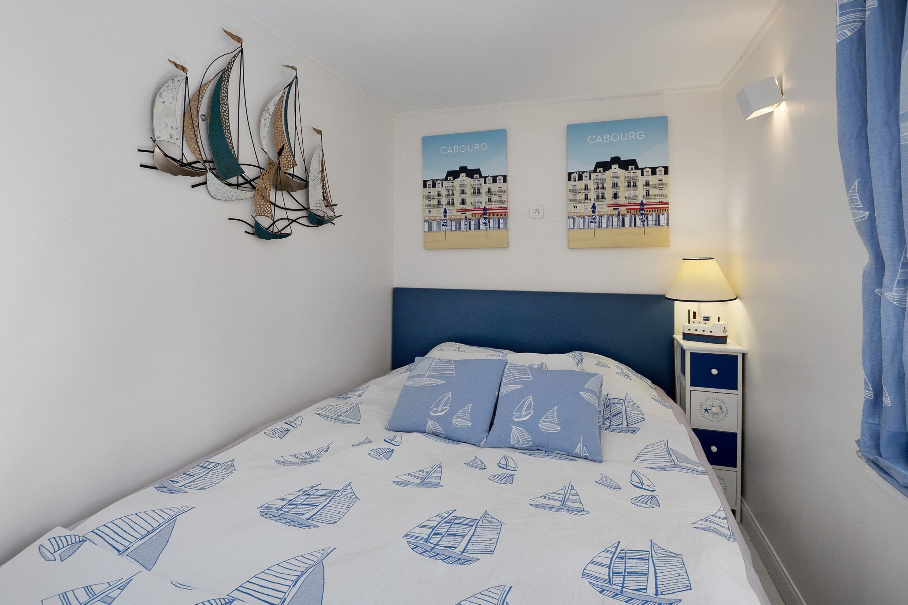 Ein Schlafzimmer mit einem Bett, einem Nachttisch, einer Lampe und Wandbildern.
