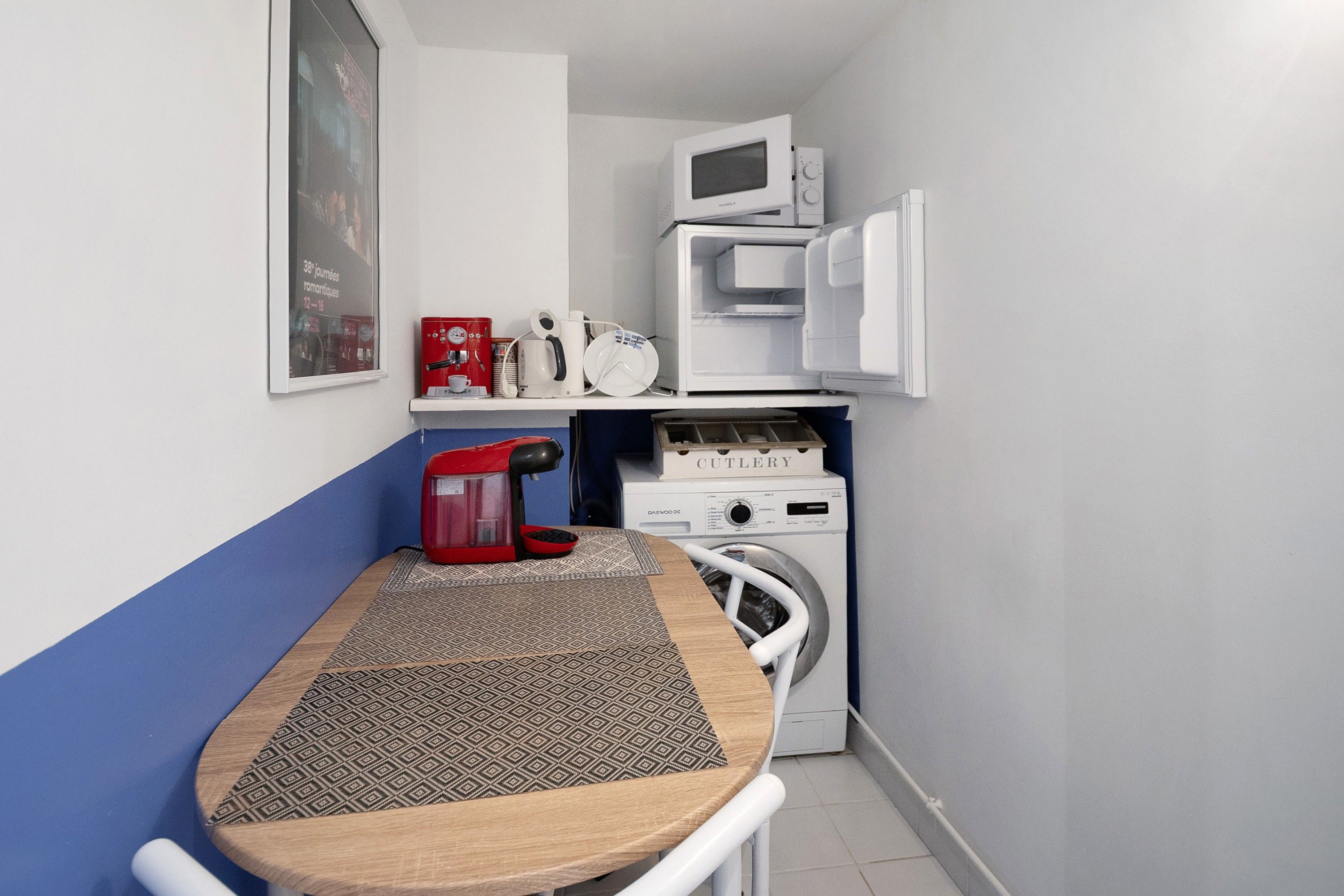 Une petite cuisine équipée d’un four à micro-ondes, d’une machine à café et d’un lave-linge.