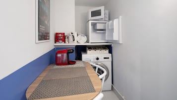 Une petite cuisine équipée d’un four à micro-ondes, d’une machine à café et d’un lave-linge.