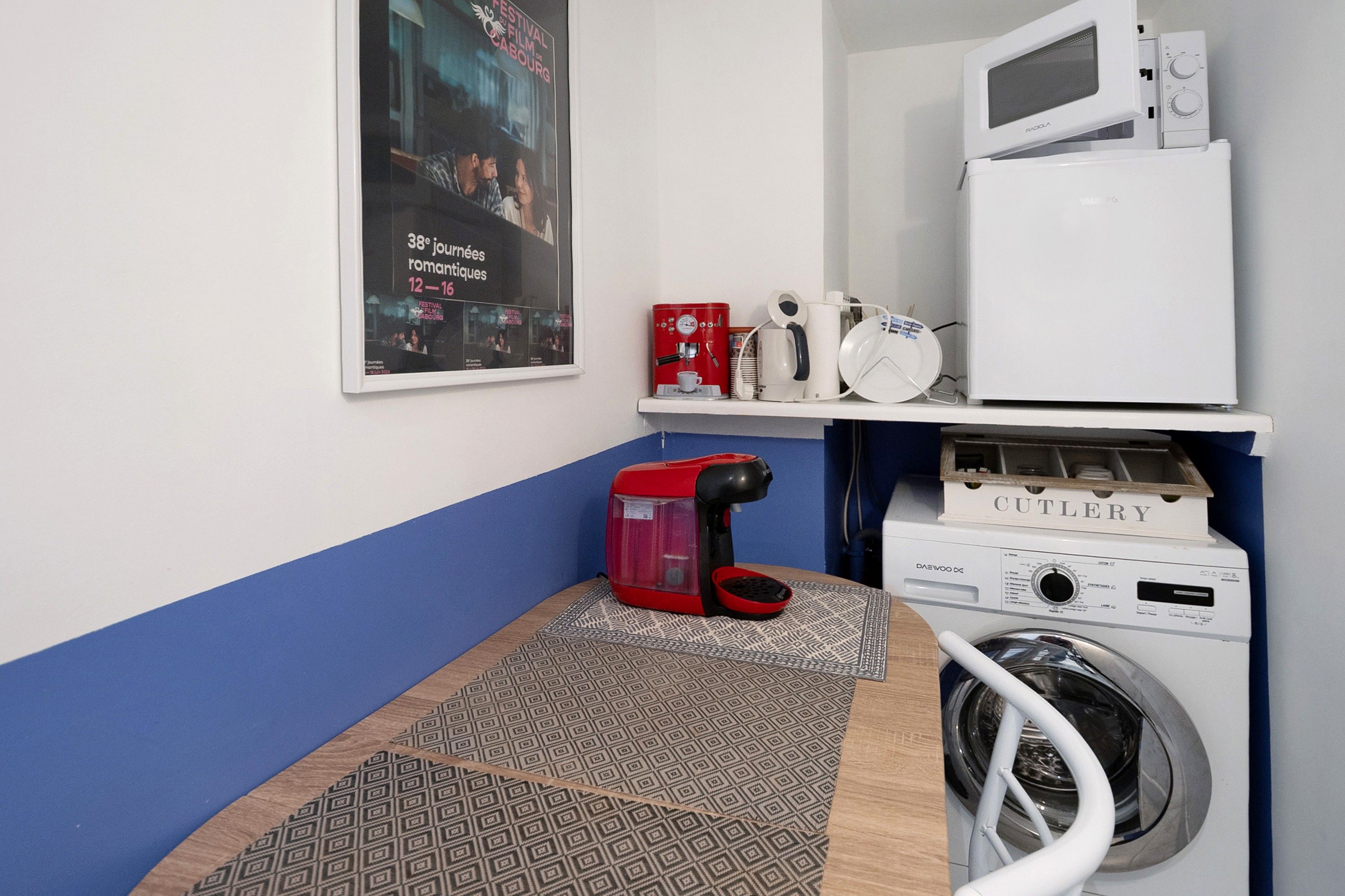 Een wasruimte met een wasmachine, een magnetron en een koffieapparaat.