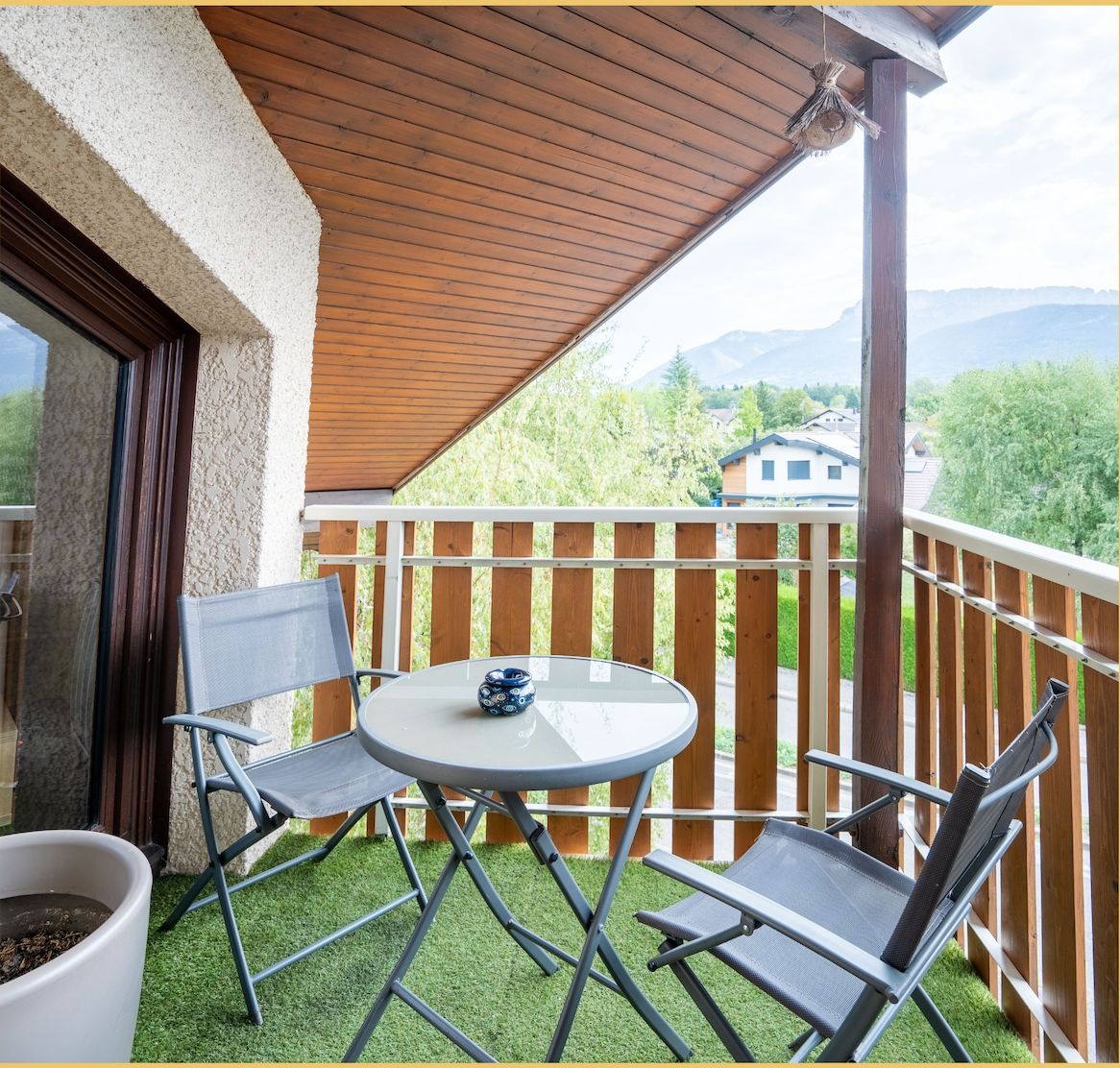 A balcony with a table, two chairs, and a potted plant.