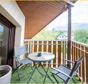 Ein Balkon mit Tisch, zwei Stühlen und einem Blumentopf.
