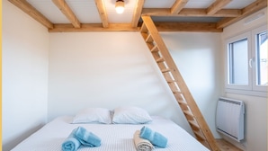 Quarto com cama, escada de madeira e janela.