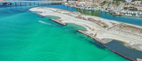 An aerial view of a coastal area with a marina, a large hotel, and a bridge.