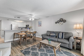 A modern living room with a gray sofa, wooden dining table, and a ceiling fan. - Sundestin 1803 (Destin)