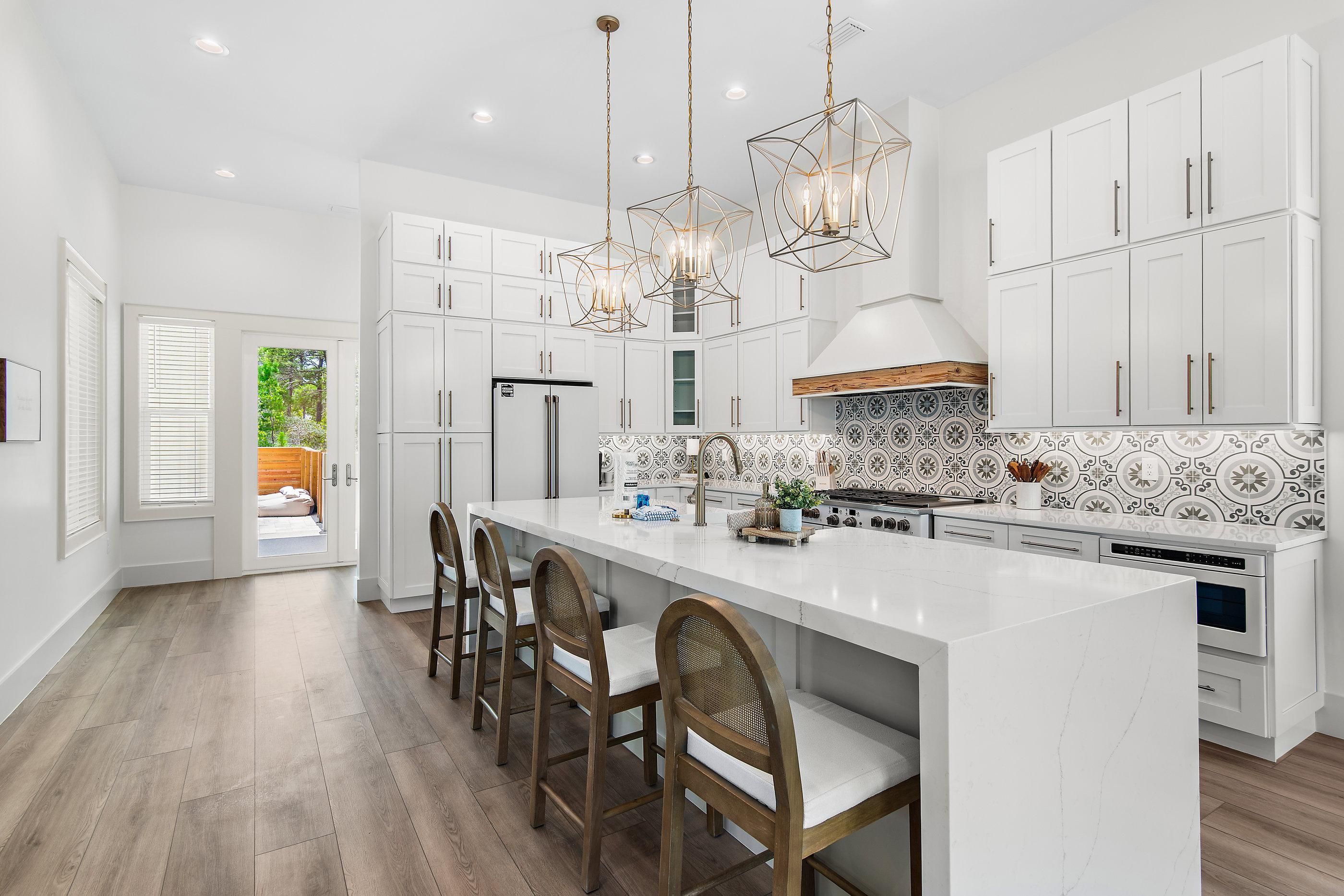 Een moderne keuken met witte kasten, een groot eiland en een patroon backsplash.