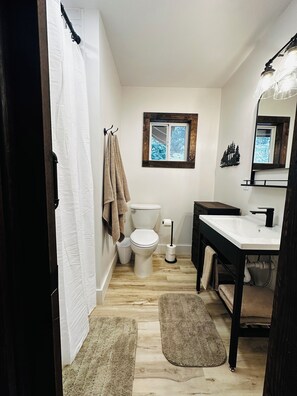 Une salle de bain avec des toilettes, un lavabo et une fenêtre.