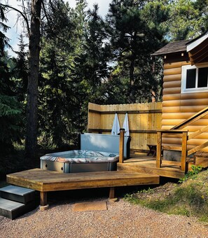 Une cabane en bois avec un jacuzzi et une terrasse.