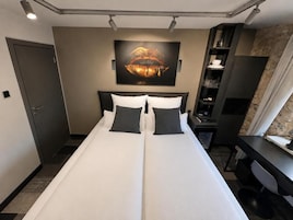 Una habitación de hotel con cama, escritorio, armario y un cuadro con labios en la pared.