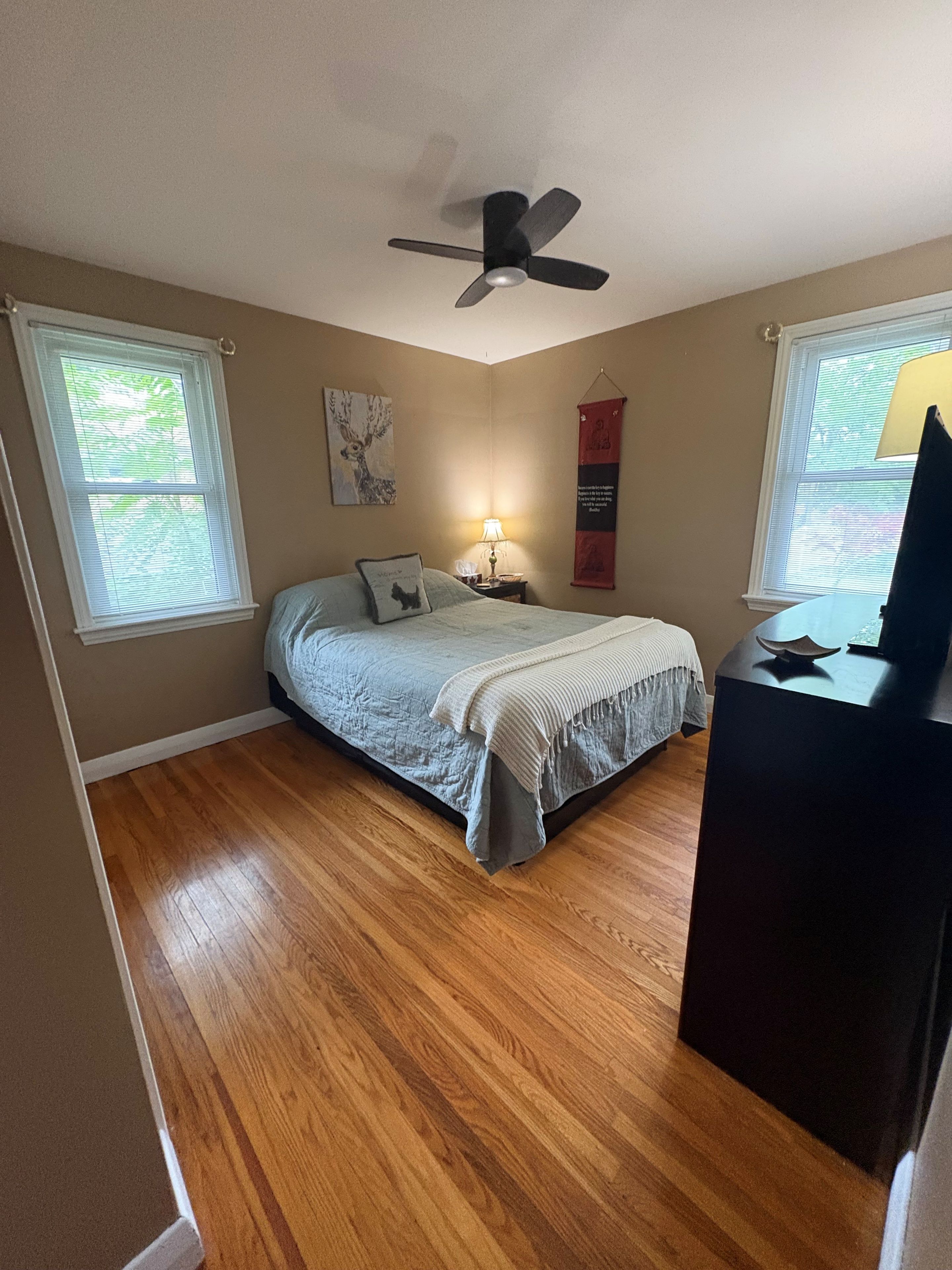A bedroom with a bed, a ceiling fan, a nightstand, a lamp, and a TV.