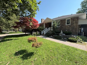A residential house with a stone facade, a front porch, and a well-maintained lawn.