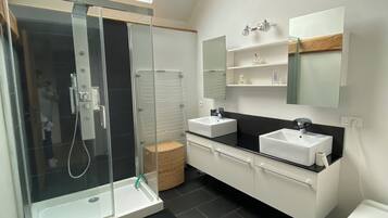 Un baño moderno con ducha de vidrio, lavamanos blanco y un inodoro.