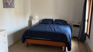 Un dormitorio con cama, mesitas de noche, un espejo en la pared y una obra de arte en la pared.